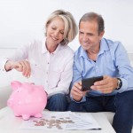 Mature Couple Calculating Coin In The Piggybank