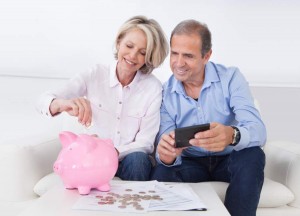 Mature Couple Calculating Coin In The Piggybank